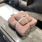 Ultra-Absorbent Coral Fleece Bath & Hand Towel Set in pink, neatly tied with a ribbon, placed on a marble countertop.