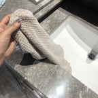 Ultra-Absorbent Coral Fleece Bath & Hand Towel Set in Pineapple Grid Collection, held above a sink with water.