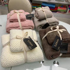Ultra-Absorbent Coral Fleece Bath & Hand Towel Set in various colors, neatly stacked with ribbons and tags on a table.