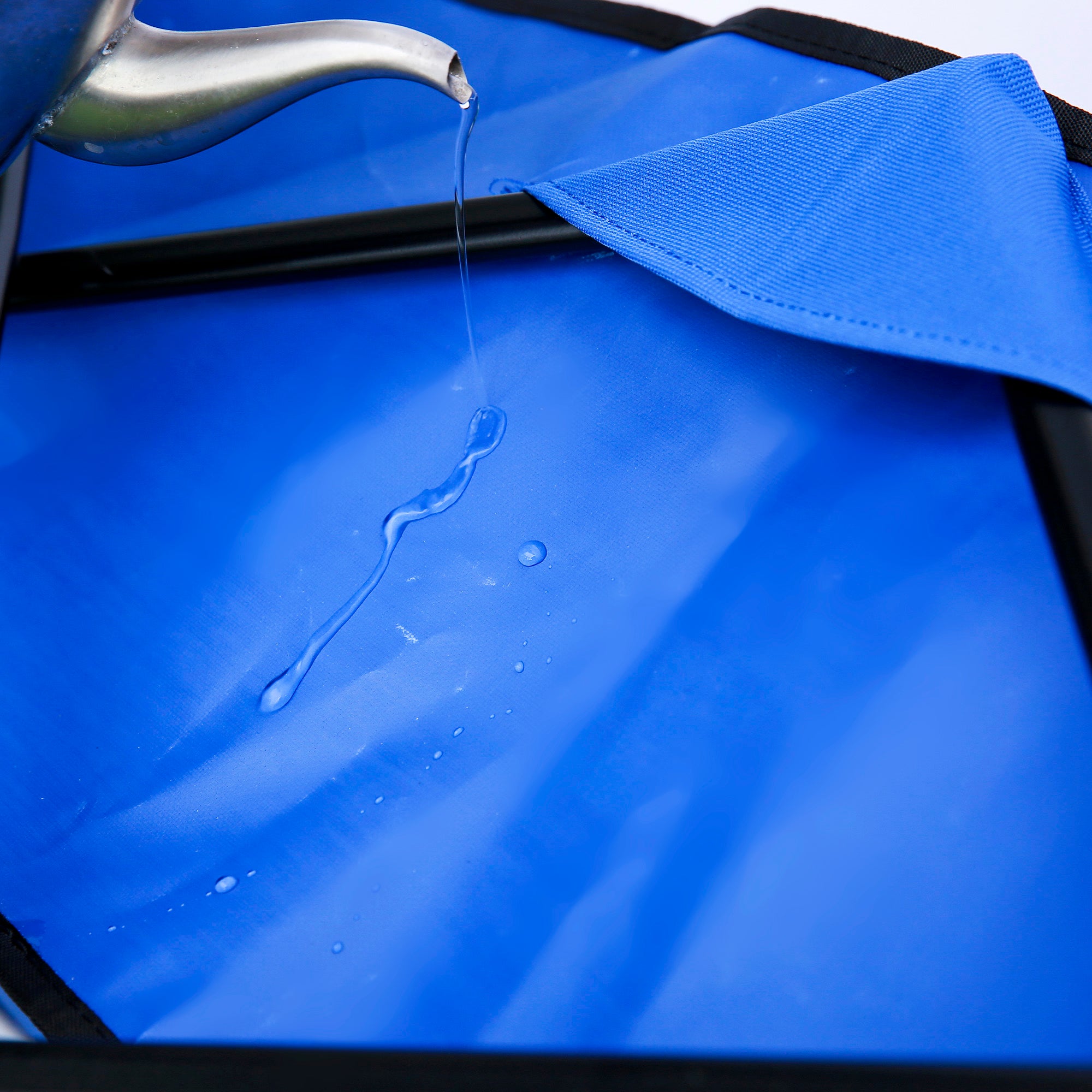 Heavy Duty Folding Utility Wagon with a blue interior, showing water being poured into the cart's fabric.
