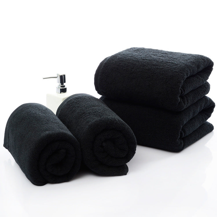 Luxury 100% Cotton Black Terry Bath & Face Towels stacked and rolled, with a soap dispenser in the center.