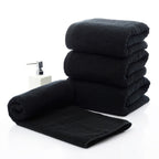 Luxury 100% Cotton Black Terry Bath & Face Towels stacked with a rolled towel and a soap dispenser beside them.