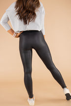 Black Faux Leather Skinny Leggings from ClassyFashionz, styled with a gray top and white sneakers, showcasing a sleek fit.